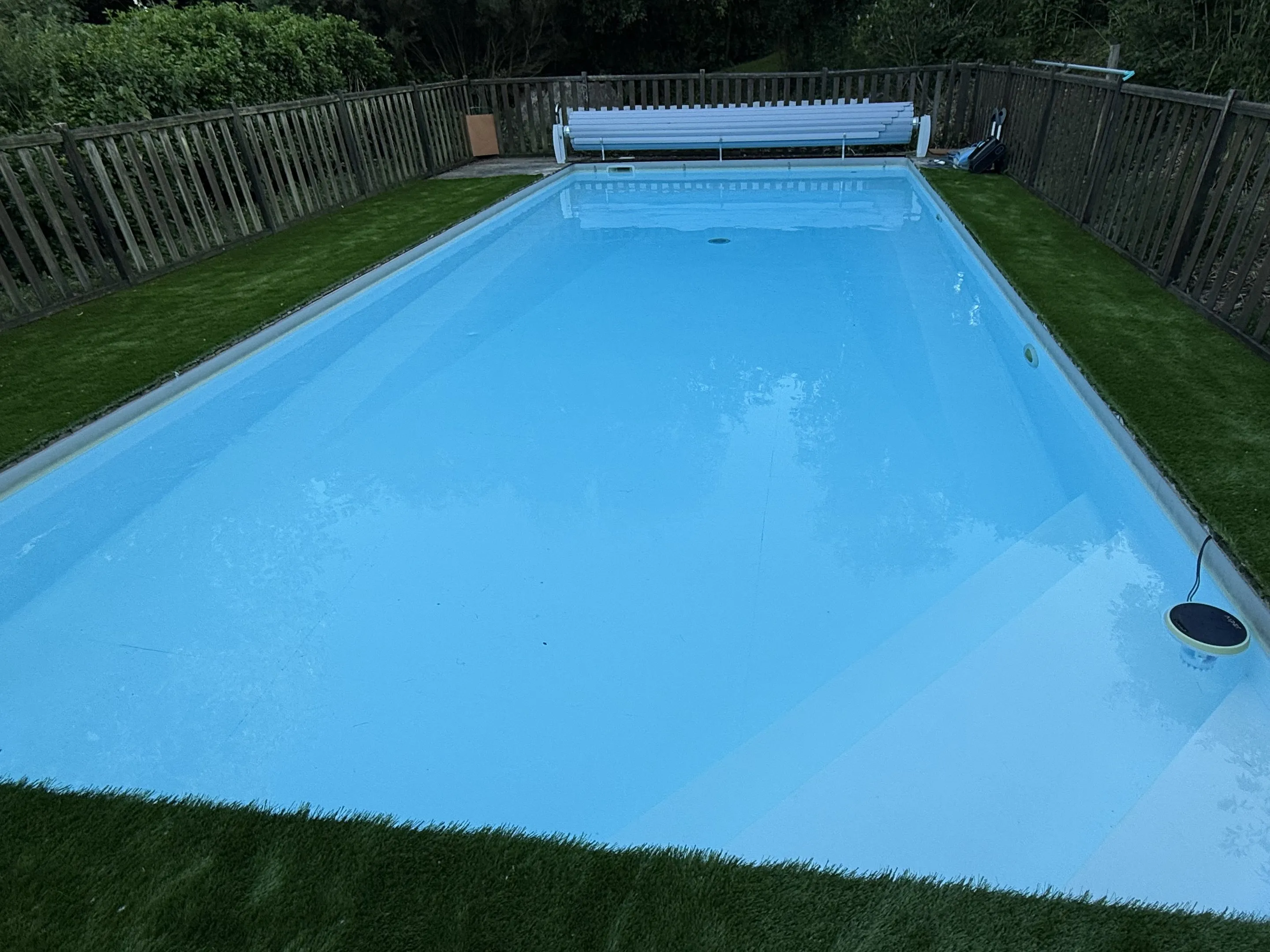 La piscine clôturée au milieu de la pelouse